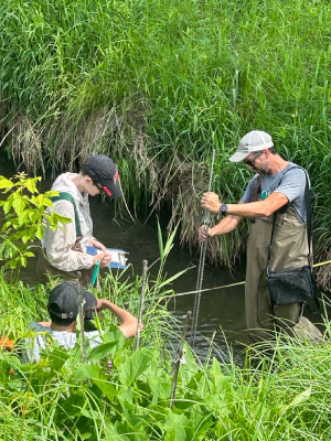 WRM students Norman Arif Muhammad, Alayne Kulp, and Jake Pinion work to collect streamflow data in a tributary of Fancy Creek. Photo by Madilyn Marti