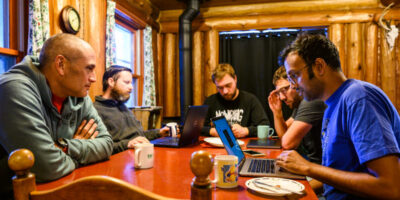 During a dawn team meeting at UW-Madison’s Kemp Natural Resources Station in Woodruff, Wis., still-sleepy staff review CHEESEHEAD project plans for the day. The regional area is the site of the CHEESEHEAD (Chequamegon Heterogeneous Ecosystem Energy-balance Study Enabled by a High-densityExtensive Array of Detectors) field experiment and research project, led by Ankur Desai (pictured at right). Photo by Jeff Miller / UW–Madison