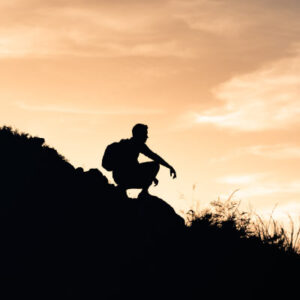 Person hiking overlooking sunset. Photo by iStock / KieferPix