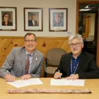 UW–Madison Interim Chancellor Scholz and College of Menominee Nation President Christopher Caldwell sign the third iteration of the transfer agreement.