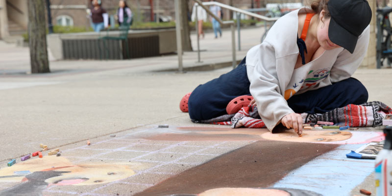 Laila Smith art chalking outside of Earth Fest headquarters.