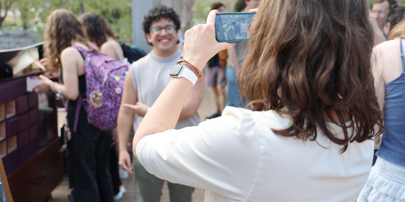 Angel Salas poses for a picture to celebrate the installation of a solar little free library at Allen Centennial Garden.