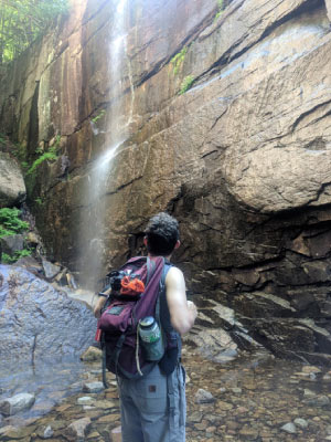 Meeker standing at the bottom of a small waterfall in the White Mountains in New Hampshire.