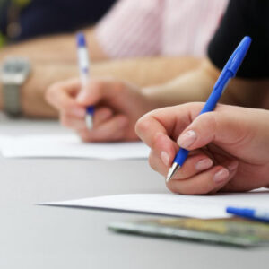People writing writing at a table. Photo by iStock / slexp880