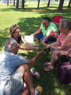Ho-Chunk elders Woody White, wanagira, Ho-Chunk for “has walked on,” (left) Marie Lewis (right), and Dawn Decorah (second from right) are pictured here with Conaway (second from left) doing a botany activity with wamaxe, wild ginger (Asarum canadense). Photo credit: Michelle Cloud