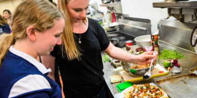 A pair of student participants prepare a platter of nachos supreme made with roasted crickets during a Cooking with Insects workshop. Photo by Jeff Miller