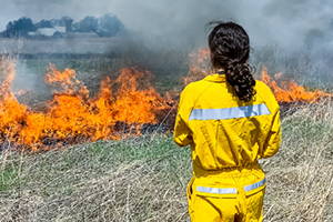 A student dressed in fire-resistant gear observing a controlled burn