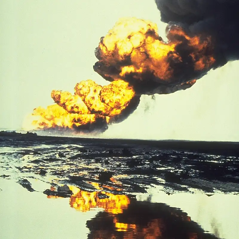 Plumes of flame and black smoke rise from the horizon in an oil field fire.
