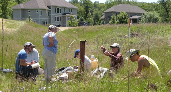 A group of scientists conducting water testing in a suburban field