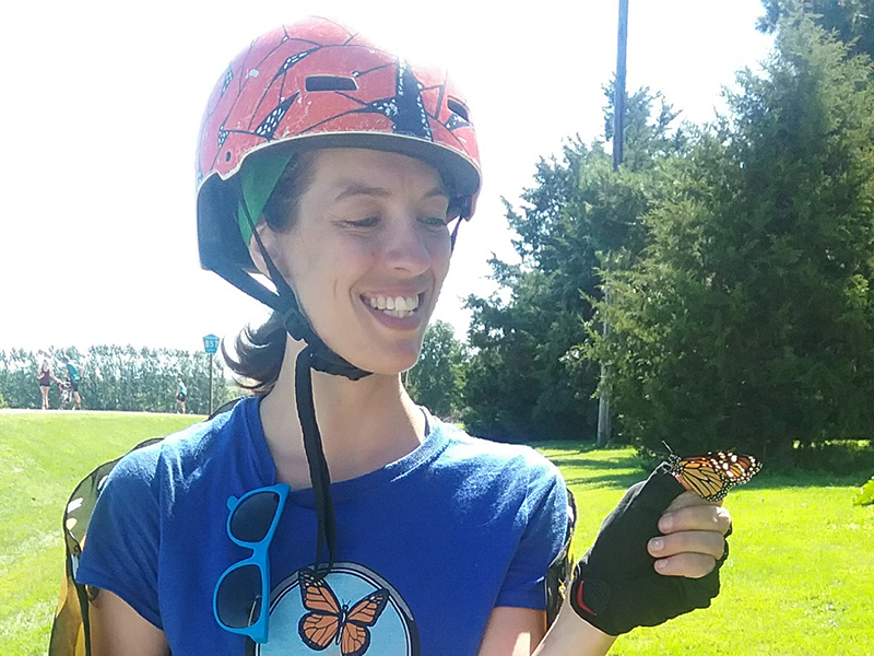 A student looking at a monarch butterfly perched on her hand