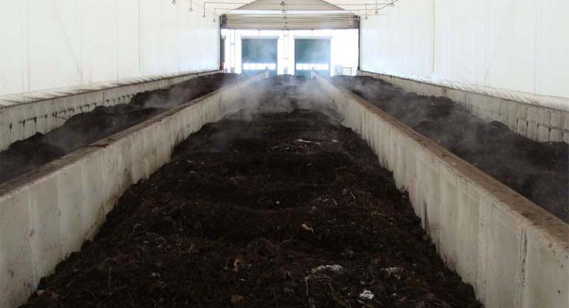 Long rows of compost pile up in a covered shelter