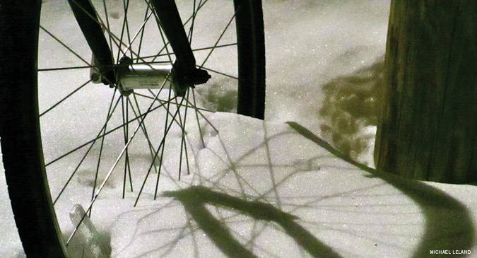 A bike wheel partially submerged in a snow bank
