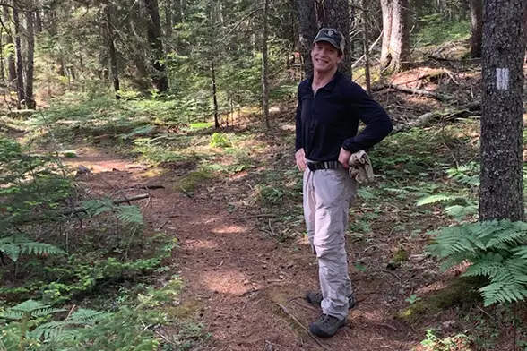 Jeff Rudd posing on a trail in an evergreen forest