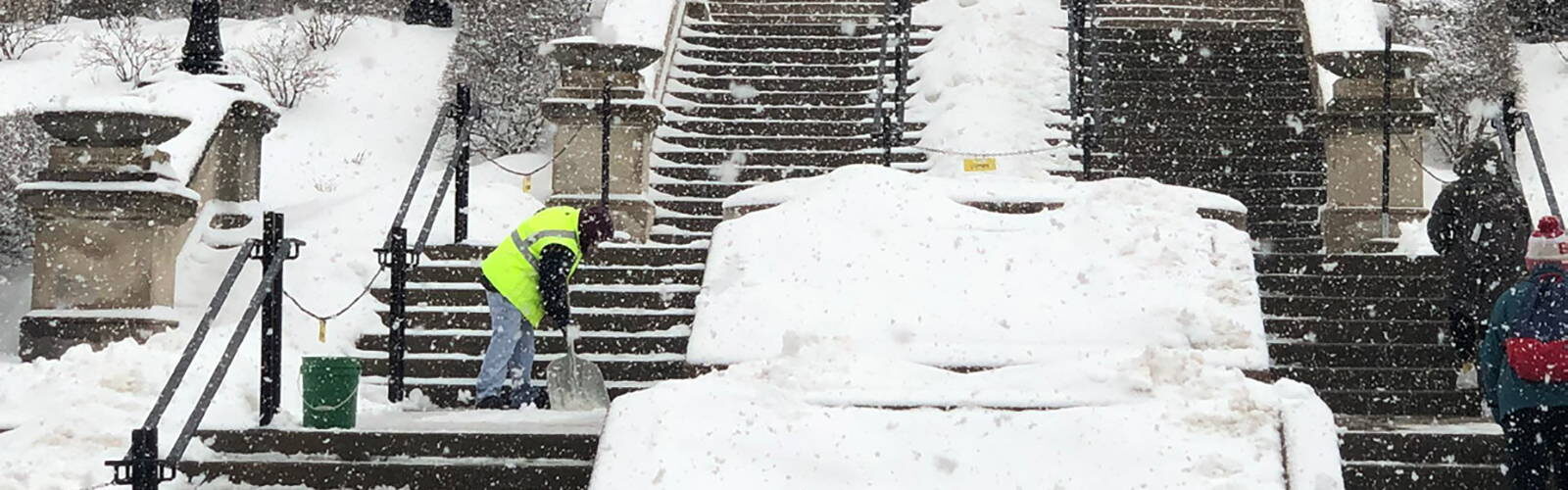 A maintenance worker shovels snow off the steep steps leading to Science Hall at UW-Madison