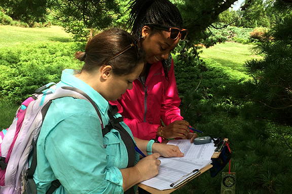 Two students writing information on a clipboard