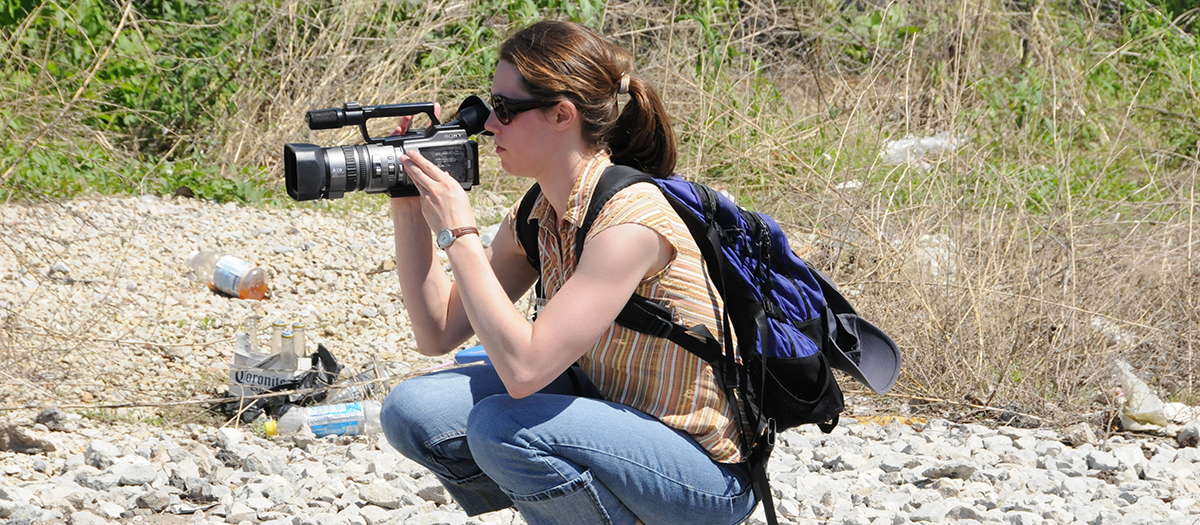A student using a video camera to film a landscape scene
