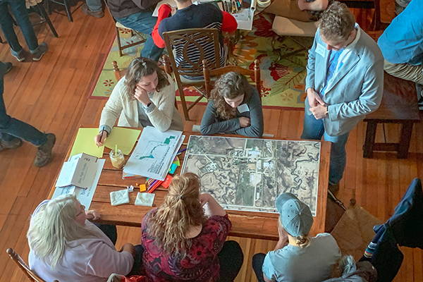 Overhead view of six people sitting around a table looking at a map